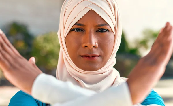 身穿军服的年轻穆斯林妇女头戴头巾 手持听诊器 双手交叉地站在医院大楼附近的街上 摆出停下来的姿势 医药和保健 — 图库照片