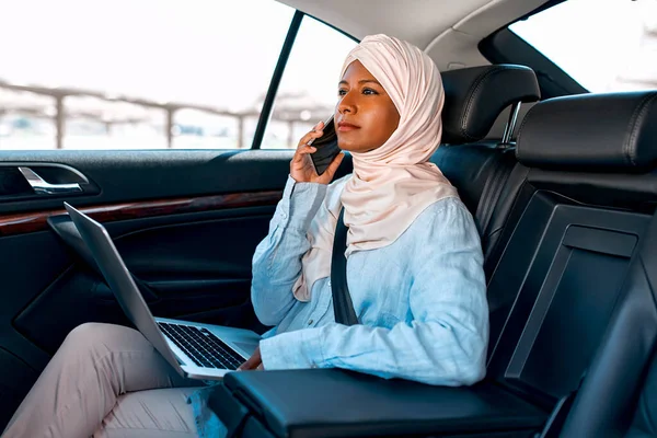車の中で座っている間 ラップトップを使用してヒジャーブの若いイスラム教徒の女性 車の中で働くイスラム教徒のビジネス女性 — ストック写真