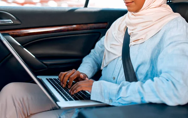 히잡을 노트북을 사용하고 있습니다 차에서 일하는 이슬람 사업가 — 스톡 사진