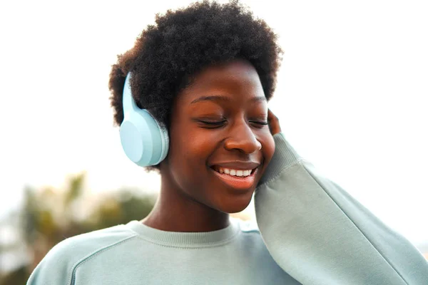 アフリカ系アメリカ人の女性が路上でアフロヘアスタイルでヘッドフォンで音楽を聴き 楽しい週末を過ごす — ストック写真