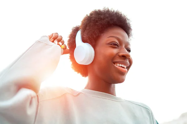アフリカ系アメリカ人の女性が路上でアフロヘアスタイルでヘッドフォンで音楽を聴き 楽しい週末を過ごす — ストック写真