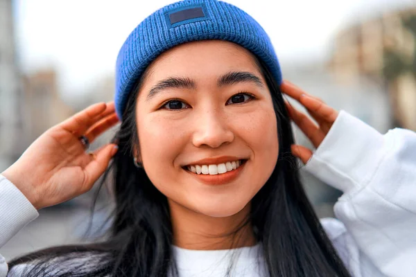 Kapıda durup gülümseyen şapkalı sevimli Asyalı genç kadın..