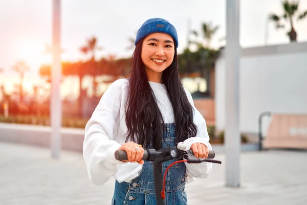 街の通りにスクーターに乗る帽子でかなりアジアの若い女性 アクティブなレクリエーションとスポーツ — ストック写真