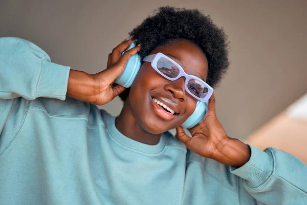 ストリートでヘッドフォンで音楽を聴くスタイリッシュなアフリカ系アメリカ人女性 — ストック写真