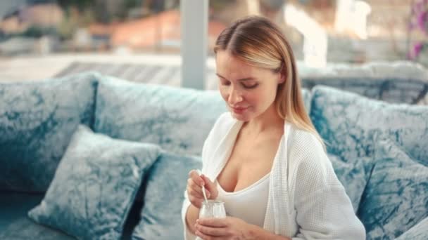 迷人的孕妇正坐在靠窗的蓝色天鹅绒沙发上 吃着酸奶 健康食品概念 怀孕的最后几个月 — 图库视频影像