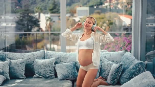 Ung Vacker Gravid Kvinna Vita Underkläder Och Badrock Med Hörlurar — Stockvideo
