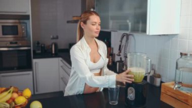 Genç hamile bir kadın mutfakta blenderla smoothie hazırlıyor. Hamile bir kadın vitamin içeceği içer. Hamilelik boyunca sağlıklı beslenme kavramı.