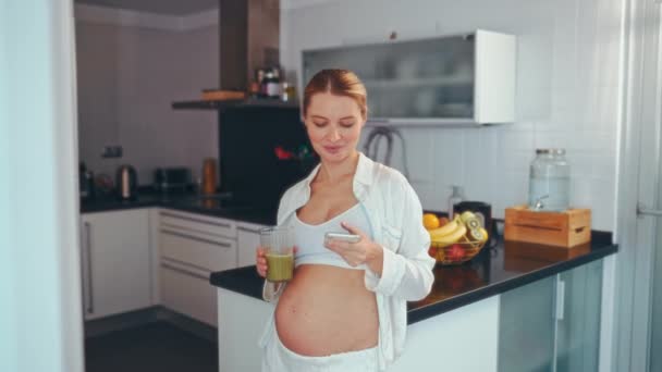 Młoda Kobieta Ciąży Pije Przygotowany Koktajl Witaminowy Używa Smartfona Stojącego — Wideo stockowe