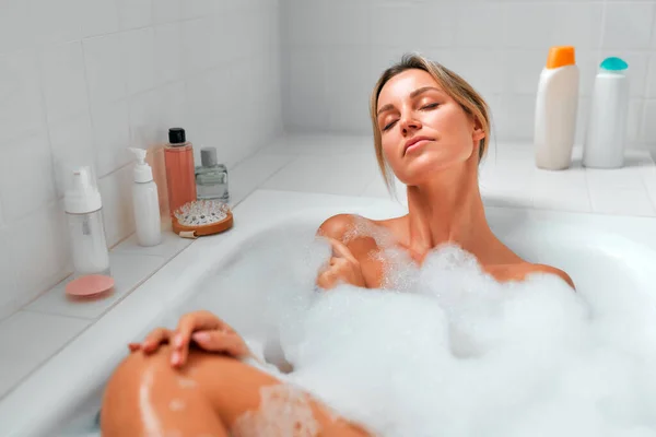 美しい女性は白い泡風呂 お楽しみとリラックスに横たわっている 朝のルーティン 美容とスパの手順 — ストック写真