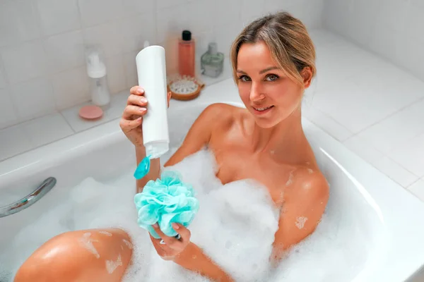 美しい女性は白い泡風呂に横たわって 洗面所とシャワージェルで入浴し 楽しんでリラックスします 朝のルーティン 美容とスパの手順 — ストック写真