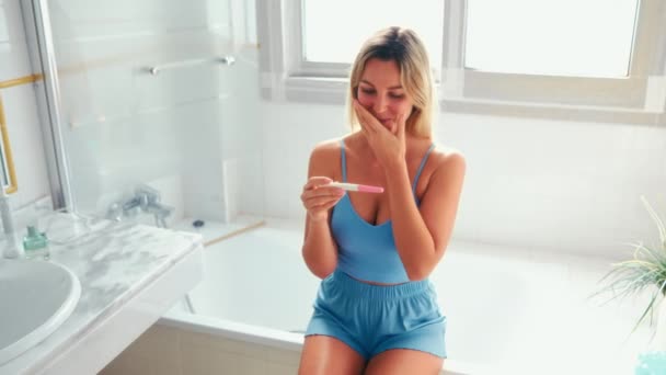 妊娠検査で浴槽の端に座っているバスルームでランジェリーの美しい女性 テストの2本の縞 幸せな女性が妊娠しました — ストック動画