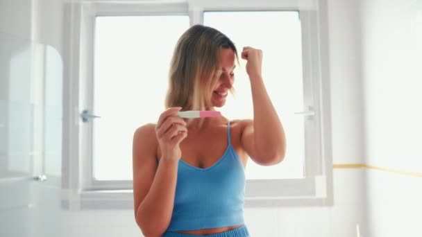 在浴室里穿着内衣的漂亮女人坐在浴缸边做孕检 两个条纹的测试 快乐快乐的女人怀孕了 — 图库视频影像