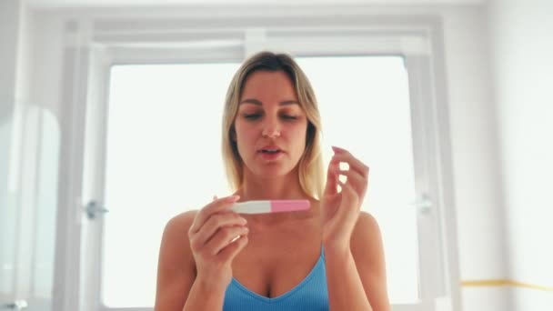 在浴室里穿着内衣的漂亮女人坐在浴缸边做孕检 两个条纹的测试 伤心的女人怀孕了 — 图库视频影像