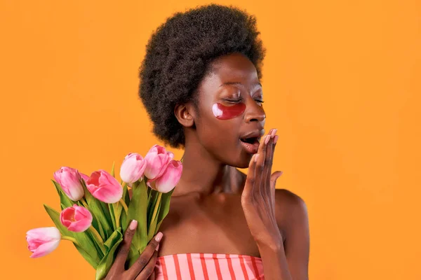 African American Young Woman Using Moisturizing Eye Patches Holding Bouquet — Stock Photo, Image