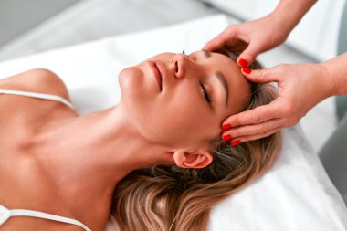 Güzellik salonundaki kadın yüz masajı için kanepede yatıyor. Masajla yüz gerdirme. Kozmetik ve cilt bakımı.