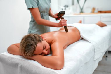 Geleneksel Tayland masajı tok-sen sırasında genç bir kadın, tahta aletlerle alternatif doğu tıbbı. Kuaförde vücut bakımı ve SPA.
