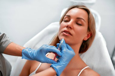 Tıbbi kozmetik tedavileri botoks enjeksiyonu. Güzellik uzmanı kadının yüzünü hyaluronik asit doldurucuyla kaplıyor. Hyaluronik asit doldurucu iğneyle ya da kanülle enjekte edilir. Yüz hatları konsepti.