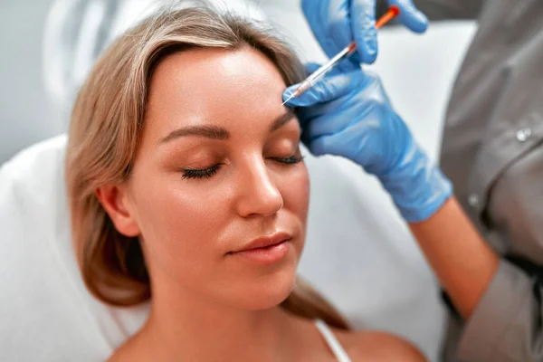 Medical cosmetology treatments botox injection. Beautician is contouring the woman\'s face with hyaluronic acid filler. Hyaluronic acid filler is injected by needle or cannula. Face contouring concept.