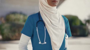 Genç Müslüman bir kadın, üniformalı, steteskoplu bir doktor, hastanenin dışında caddede duruyor. İlaç ve sağlık hizmetleri.
