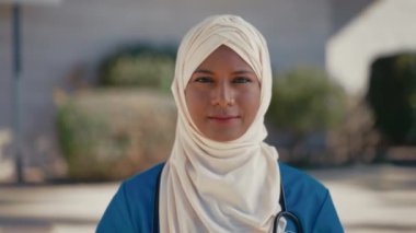 Genç Müslüman bir kadın, üniformalı, steteskoplu bir doktor, hastanenin dışında caddede duruyor. İlaç ve sağlık hizmetleri.