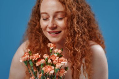 Genç kızıl saçlı, kilolu ya da çiçekli tombul bir kadın doğal bedenini kutluyor. Mavi arka planda beyaz iç çamaşırlı güzel bir kadın model. Kozmetoloji, cilt ve vücut bakımı kavramı.