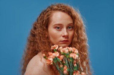 Genç kızıl saçlı, kilolu ya da çiçekli tombul bir kadın doğal bedenini kutluyor. Mavi arka planda beyaz iç çamaşırlı güzel bir kadın model. Kozmetoloji, cilt ve vücut bakımı kavramı.