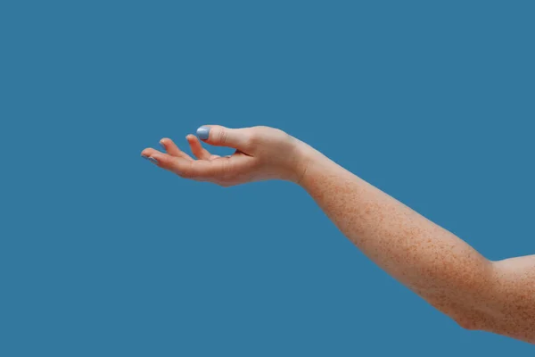 有雀斑的雌性手将手掌向上伸出 与蓝色背景隔离 复制空间 插入广告产品的位置 — 图库照片