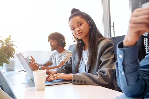 stock image Call center staff accompanied by their team. A team of freelancers working in a coworking space in a modern office. Young employees working with headset and laptop.