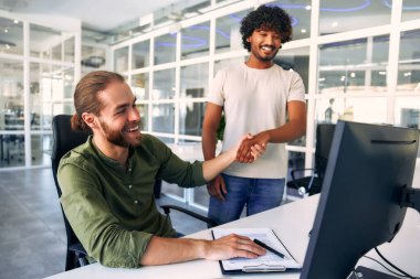 Modern bir iş yerinde bilgisayar başında oturmuş iş ve iş tartışan iki çok ırklı erkek serbest çalışan. Günlük iş, serbest iş, e-öğrenme veya e-ticaret faaliyet kavramı