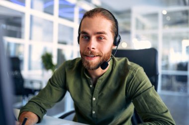 Kulaklıkla çalışan teknik destek operatörü. Çağrı merkezi operatörü olarak çalışan gülümseyen yakışıklı adam, müşteriyle konuşuyor. Video konferansı yaparken uzaktan çalışan mutlu iş adamı..