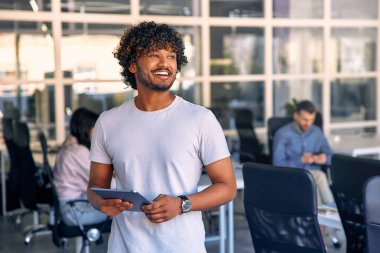 Ofisinde tabletle duran ve ekibiyle çalışan genç bir işadamı. Ortak bir çalışma alanında çalışan bir grup serbest çalışan. Başarılı insanlar birlikte iş kuruyor..