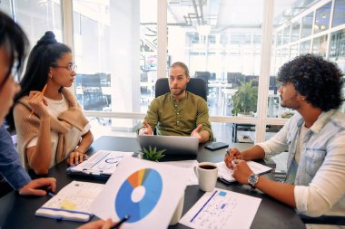 Modern ofisteki çok ırklı, yaratıcı genç insanlar. Bir grup genç iş adamı dizüstü bilgisayar, tablet, akıllı telefon ve defterle birlikte çalışıyor. Birlikte çalışan başarılı bir hipster takımı. Bağımsızlar