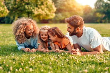 Mutlu, genç bir aile babası, anne ve iki kızı güneşli bir günde parkta çimlerin üzerinde uzanıyor, birlikte eğleniyor ve tatil günlerinde dinleniyorlar..