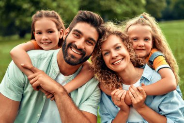 Mutlu, genç bir aile babası, anne ve iki kızı güneşli bir günde parkta çimlerin üzerinde oturmuş birlikte eğleniyor ve tatil günlerinde dinleniyorlar..