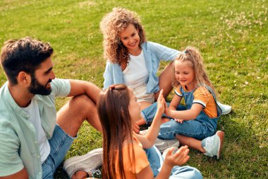 Mutlu, genç bir aile babası, anne ve iki kızı sıcak güneşli bir günde parkta çimlerin üzerinde oturuyor, birlikte eğleniyor ve eğleniyor, izin günlerinde dinleniyorlar..