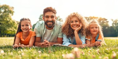 Mutlu, genç bir aile babası, anne ve iki kızı güneşli bir günde parkta çimlerin üzerinde uzanıyor, birlikte eğleniyor ve tatil günlerinde dinleniyorlar..