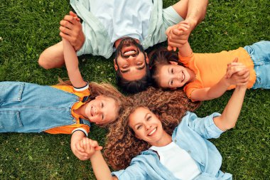Mutlu, genç bir aile babası, anne ve iki kızı güneşli bir günde parkta çimlerin üzerinde uzanıyor, birlikte eğleniyor ve tatil günlerinde dinleniyorlar..