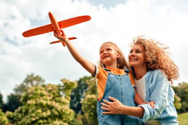 Mutlu genç anne, sevgili küçük kızıyla parkta bir çayırda oynuyordu. Sıcak ve güneşli bir hafta sonunda birlikte eğleniyorlardı..