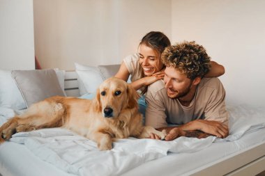 Sevgili köpekleri ile yatak odasındaki kanepede uzanmış birbirine aşık genç bir çift, hafta sonları eğleniyor ve eğleniyorlar..