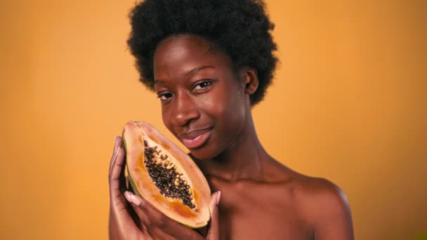 Afroamerykańska Młoda Kobieta Afro Włosami Trzymająca Papaję Dłoniach Odizolowaną Pomarańczowym — Wideo stockowe