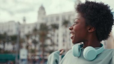 Güzel Afro-Amerikan turist kadın elinde tuttuğu ve akıllı bir telefonla kendini şehir merkezindeki bir sokağa girerken görüntülüyor. Tatilde ve yaşam tarzında teknoloji ağı kullanan kadın.
