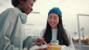 Afro-Amerikalı ve Asyalı kadın arkadaşlar kahve içiyor, eğleniyor, konuşuyor ve akıllı telefonlarından komik bir şeyler izliyorlar. İki arkadaşımla buluşacağım..