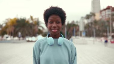 Afro saçlı, kulaklıkla müzik dinleyen Afro-Amerikalı bir kadın sokakta eğlenceli bir hafta sonu geçiriyor..