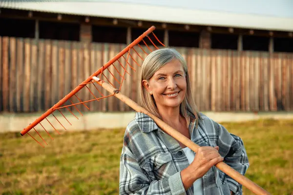 成熟美丽的女农民站在农场谷仓的后面 手里拿着叉子 农业和农业概念 — 图库照片