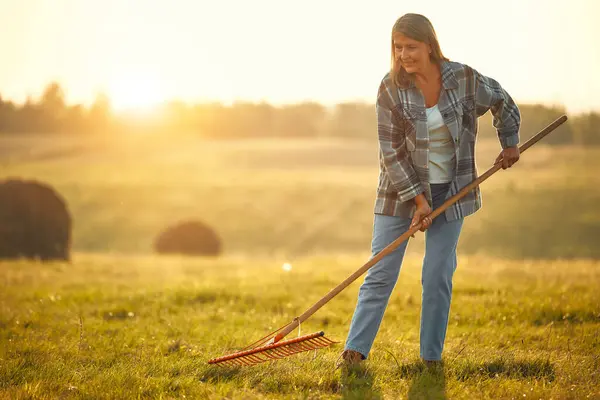 炎热的一天 在农场干活时 一个成熟美丽的女农民拿着叉子站在田边 农业和农业概念 — 图库照片