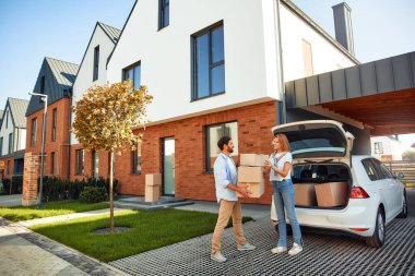 Genç evli bir çift arabadan kutularca eşya boşaltıp onları yeni bir eve taşır. Kiralamak ve bir ev almak. Taşınma konsepti.
