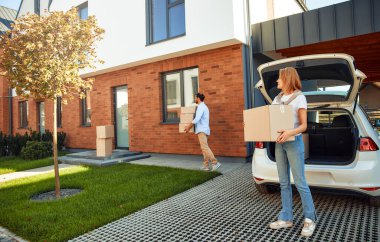 Genç evli bir çift arabadan kutularca eşya boşaltıp onları yeni bir eve taşır. Kiralamak ve bir ev almak. Taşınma konsepti.