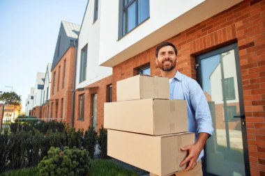 Elinde bir yığın kutu olan çekici genç bir adam onları yeni evine getiriyor. Kiralamak ve bir ev almak. Taşınma konsepti.