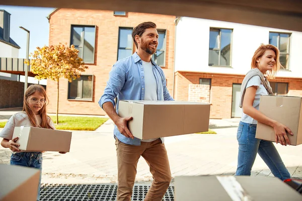 Genç evli bir çift ve kızları arabadan kutularca eşya indirip yeni bir eve taşıyorlar. Kiralamak ve bir ev almak. Taşınma konsepti.