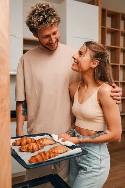 stock image Young couple in love baking croissants in the kitchen together, preparing for breakfast, talking and spending time romantically together.